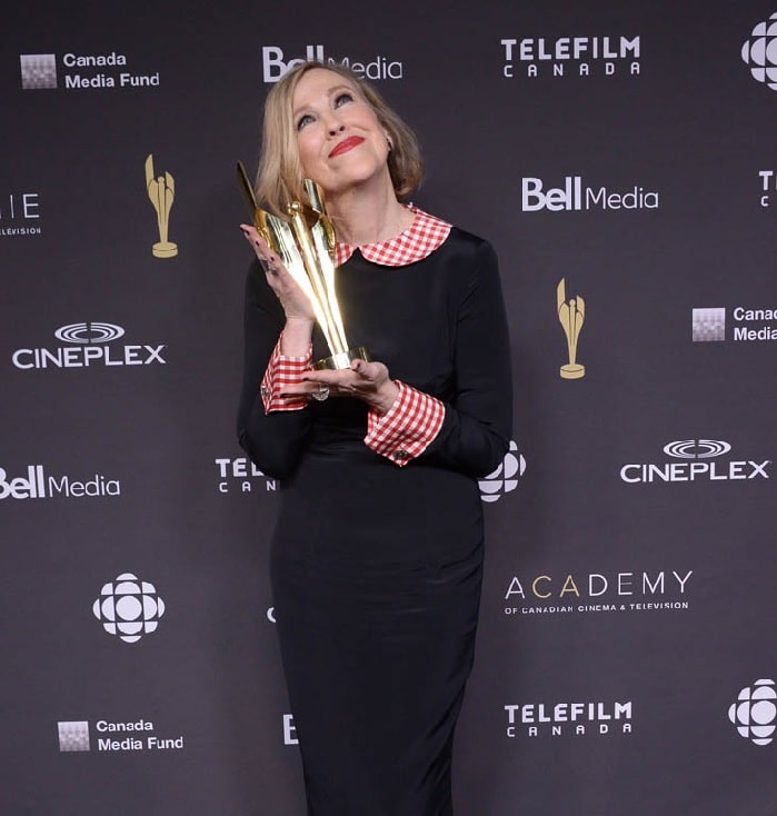 Catherine O'Hara wearing black dress while looking up and smiling holding her golden Canadian Screen Award
